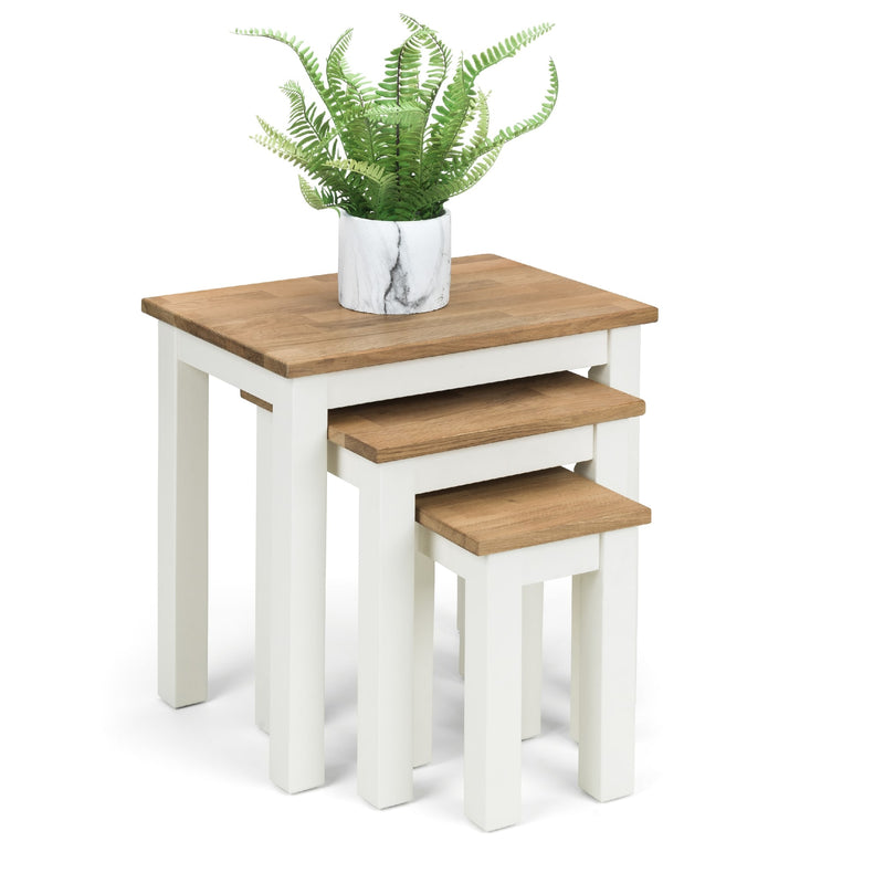 Set of three nesting tables with wooden tops and white bases, one with a potted plant.