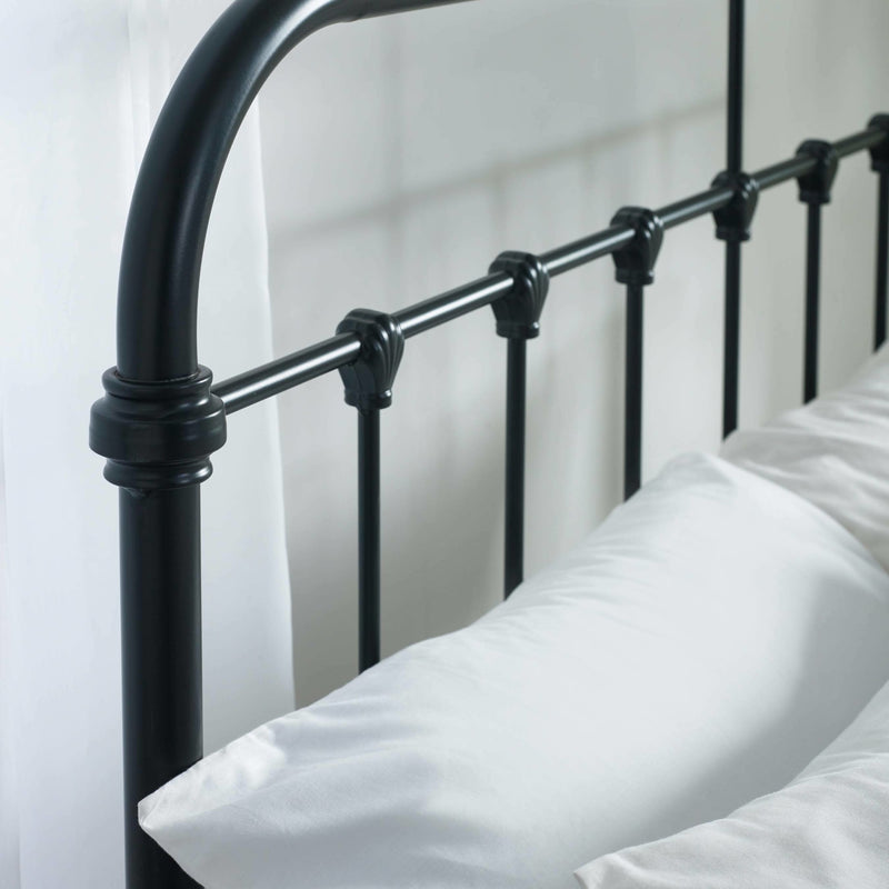 Black metal bed frame with white pillows against a white background