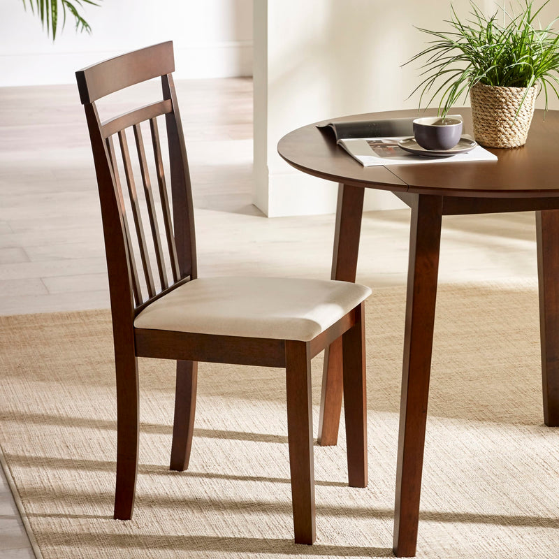 Wooden chair with a cushion next to a round wooden table in a bright room.