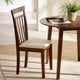 Wooden chair with a cushion next to a round wooden table in a bright room.