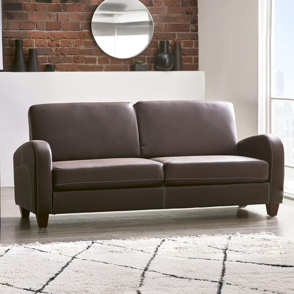 Brown sofa in a living room with a brick wall and mirror.