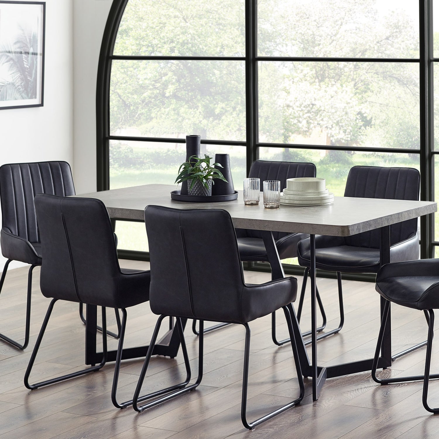 Dining table with chairs in a modern room with large windows