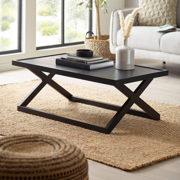 Modern black coffee table in a living room setting with decor items on top.
