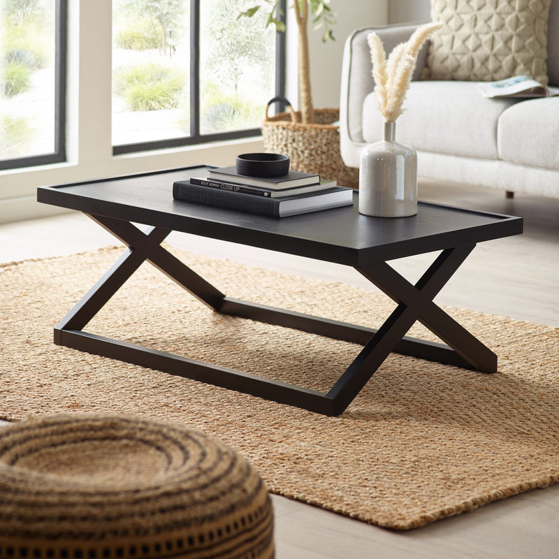 Modern black coffee table in a living room setting with decor items on top.