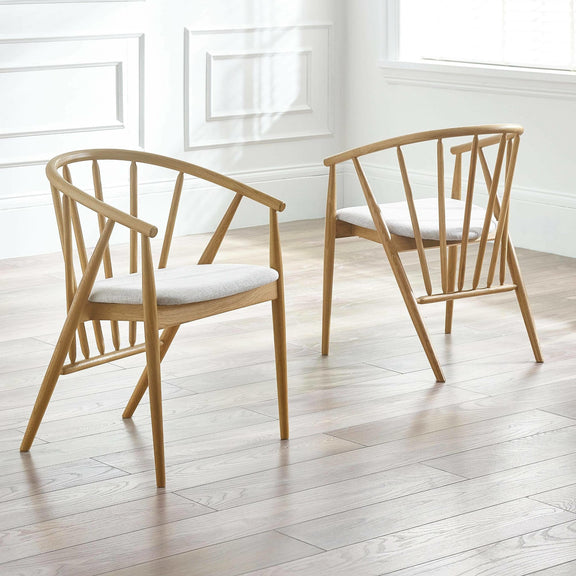 Two wooden chairs with white cushions on a light wooden floor.