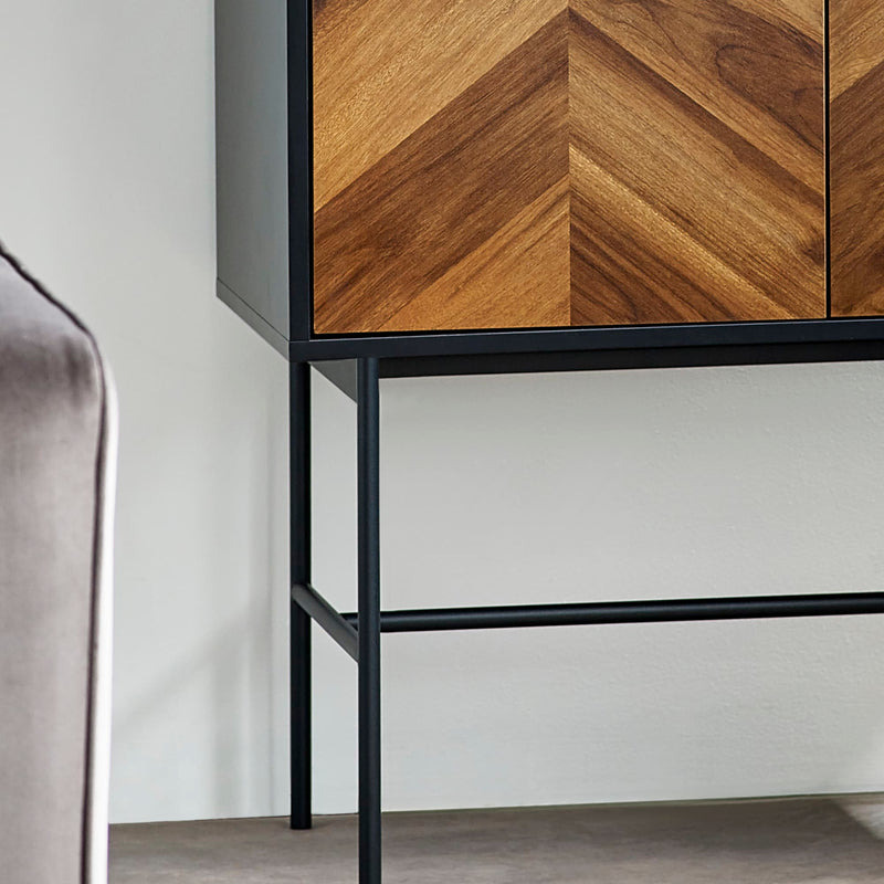 Cabinet with wooden chevron pattern doors and black metal frame against a white wall.
