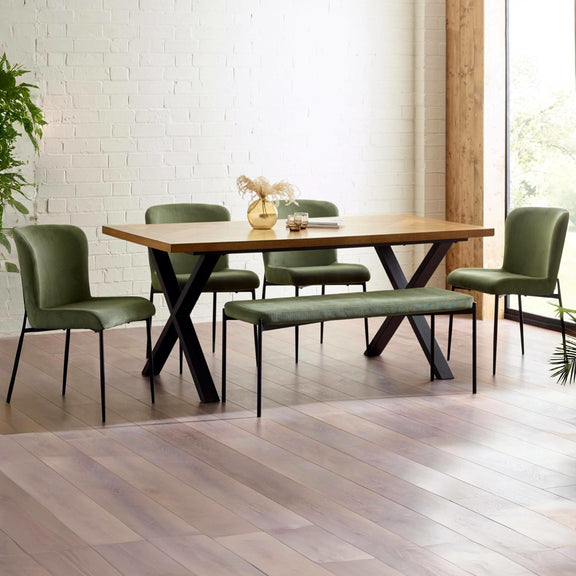 Dining room with wooden table and green chairs against a white brick wall.