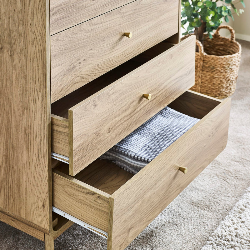 Wooden dresser with open drawer revealing a folded blanket, in a home setting.