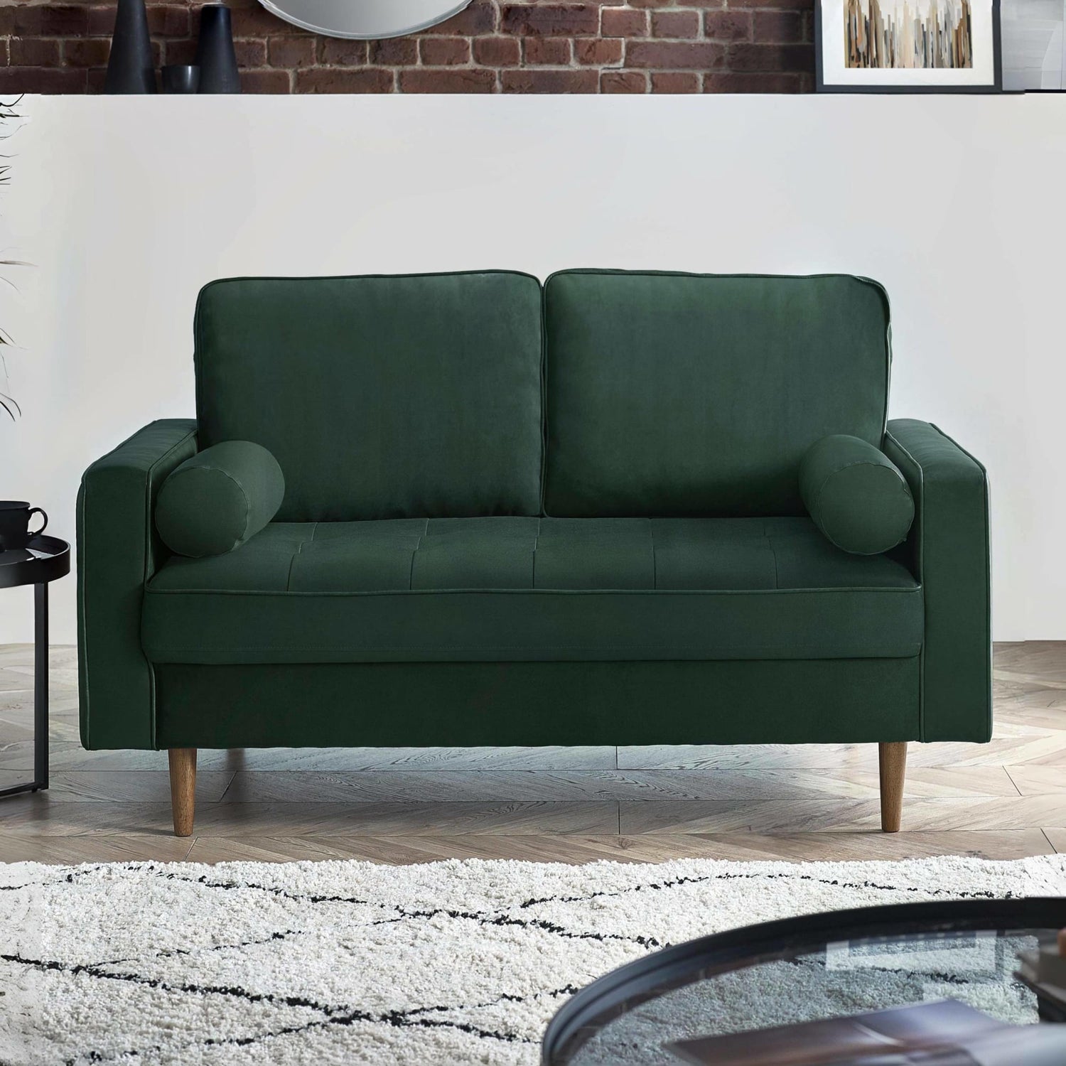 Green sofa in a living room setting with a white wall and wooden floor.