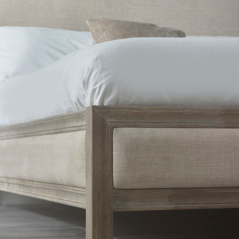 Beige upholstered bed with white bedding in a neutral room setting