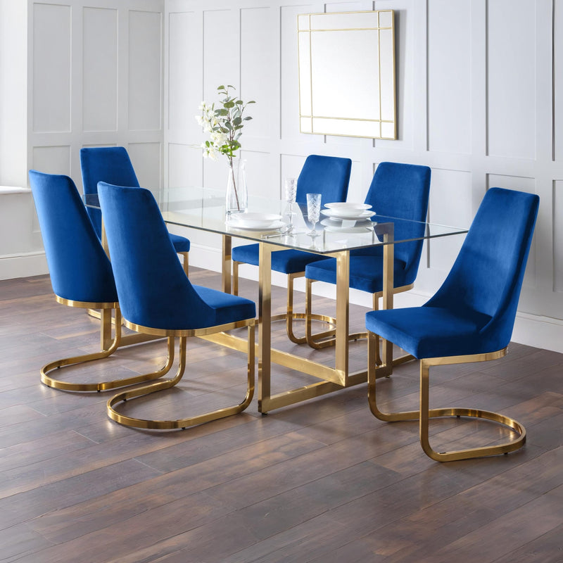 Dining room with a glass table and blue chairs with gold legs.