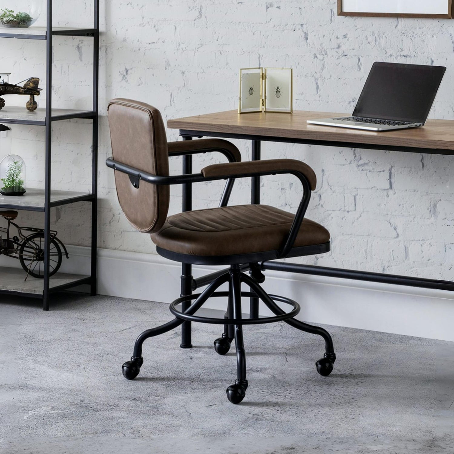 Brown office chair in front of a wooden desk with a laptop, against a white brick wall.