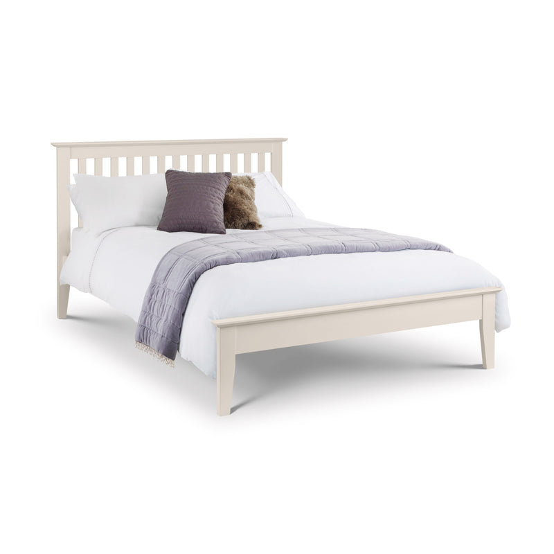 White bed with white bedding and a purple pillow on a white background