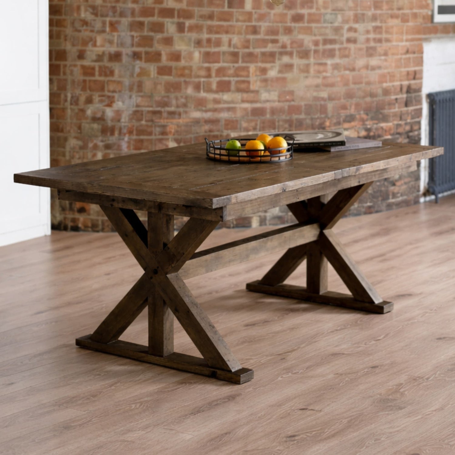 Wooden dining table with a rustic design in a room with brick walls.