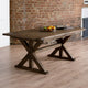 Wooden dining table with a rustic design in a room with brick walls.