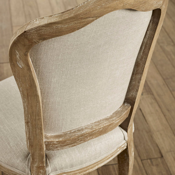 Close-up of a wooden chair with beige fabric seat and backrest on a wooden floor.