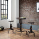Set of industrial-style stools and a table against a brick wall.