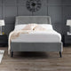 Gray upholstered bed with white bedding in a room with dark gray walls and wooden flooring.