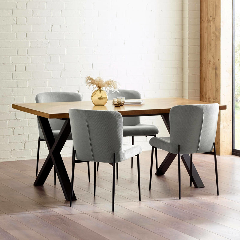 Dining table with four gray chairs in a room with white brick walls and wooden flooring.