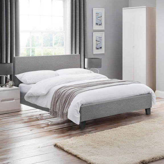 Modern bedroom with gray upholstered bed, white bedding, and wooden flooring.