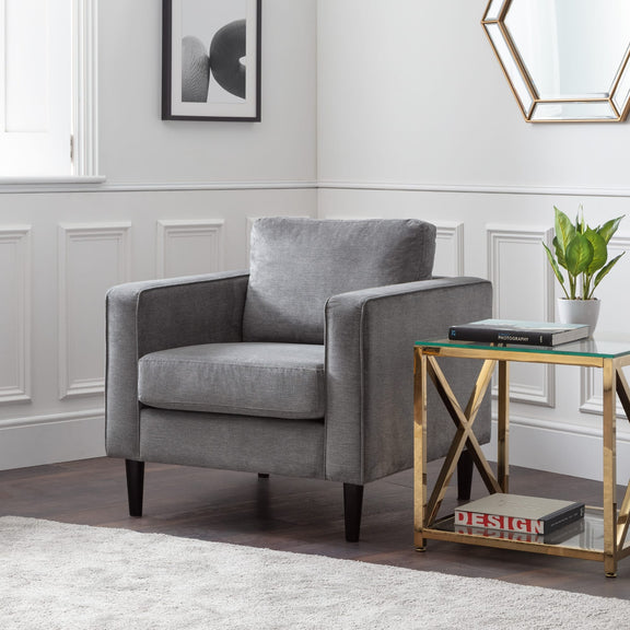 Gray armchair in a living room with a side table and decorative items.