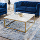 Blue velvet sofa and coffee table with marble top and gold legs in a living room setting.