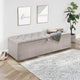 Gray upholstered storage bench in a room with a plant, rug, and wall art.