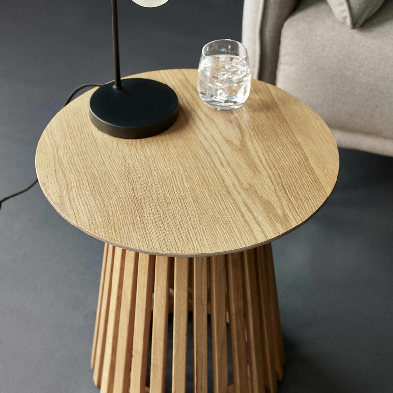 Wooden side table with a black lamp and glass of water on a dark gray background