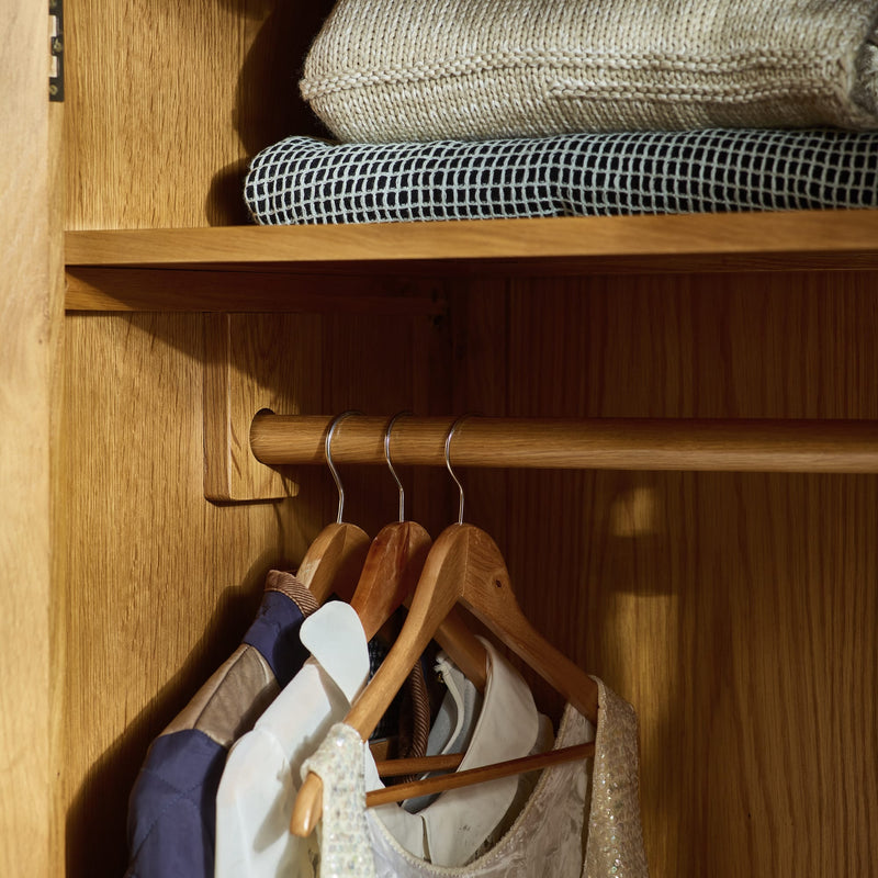 Closet with wooden shelves and hangers holding clothes