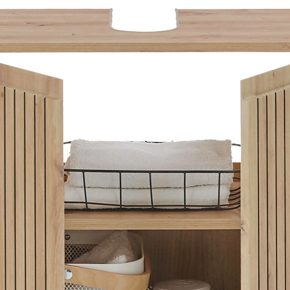 Wooden cabinet with a wire basket containing white towels and other items.