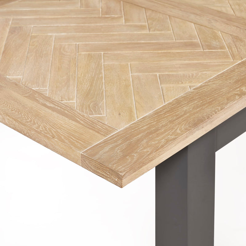 Wooden table with herringbone pattern and metal legs on a white background