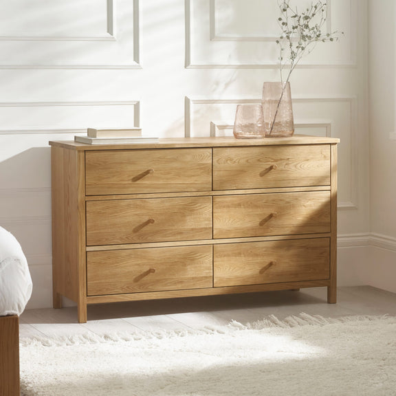 Wooden dresser with four drawers in a bedroom setting