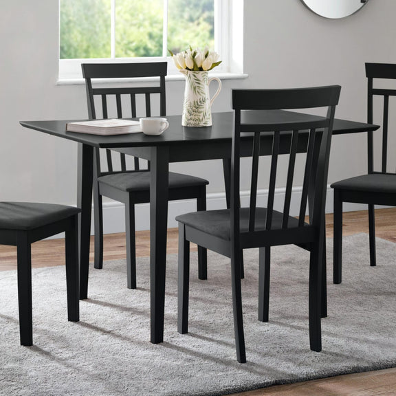 Black dining table set with chairs in a room with a window and rug.