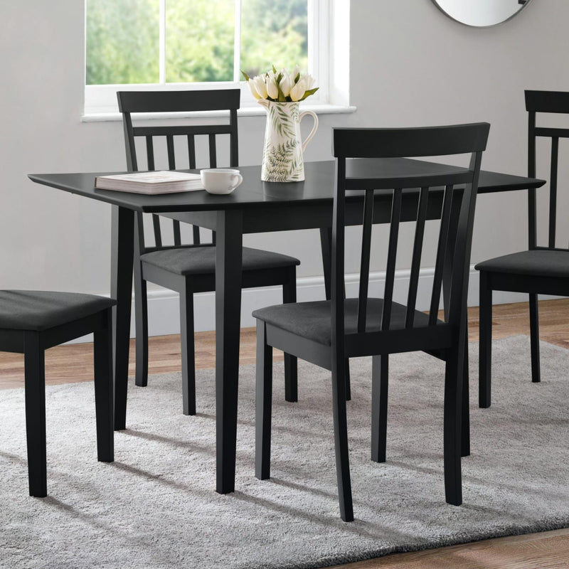 Black dining table set with chairs in a room with a window and rug.