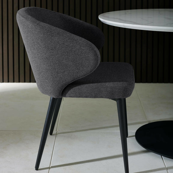 Gray upholstered chair with black legs in a minimalistic setting