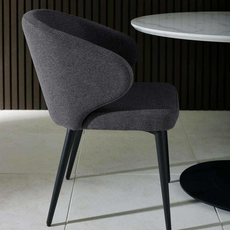 Gray upholstered chair with black legs in a minimalistic setting
