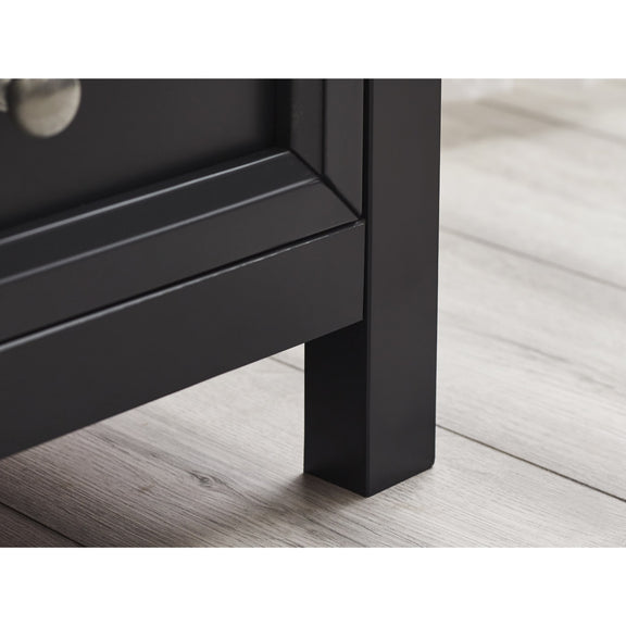 Close-up of a black metal leg on a piece of furniture, likely a bed or table, with a light wood floor background.