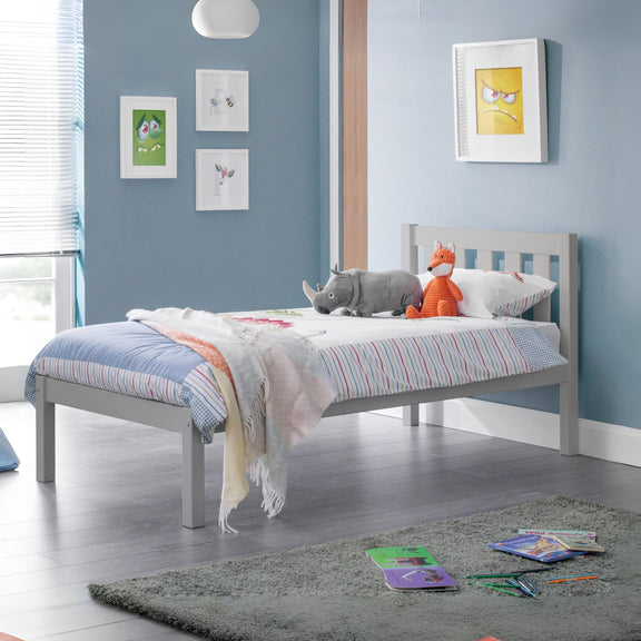 Children's bedroom with a bed, toys, and colorful bedding against a blue wall.