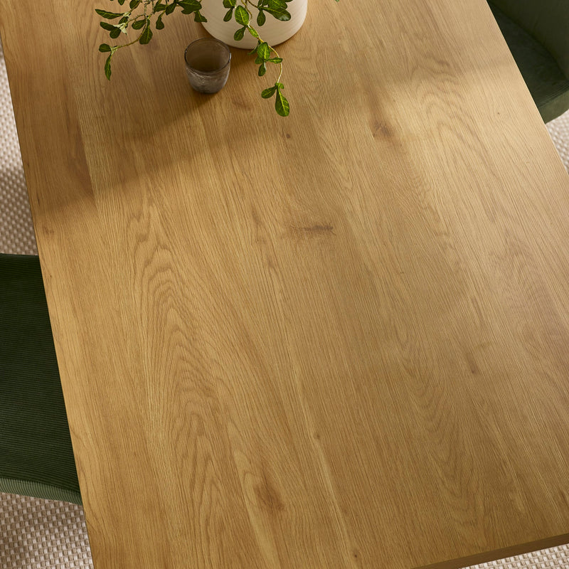 Wooden table surface with a plant and decorative items on a textured floor.