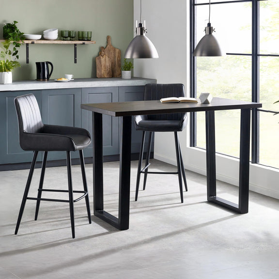 Modern kitchen with a black dining table and bar stools, featuring a green wall and large windows.