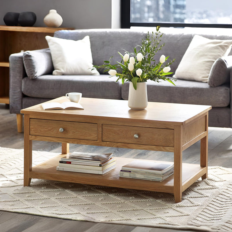 Wooden coffee table with a vase of flowers and books in a living room setting.