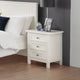 White nightstand with decorative items next to a bed with white bedding and a dark headboard.