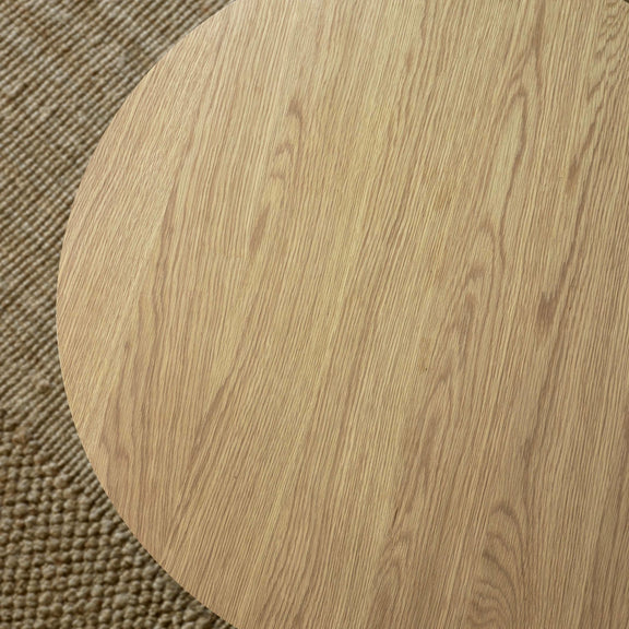 Close-up of a wooden round table corner on a textured surface