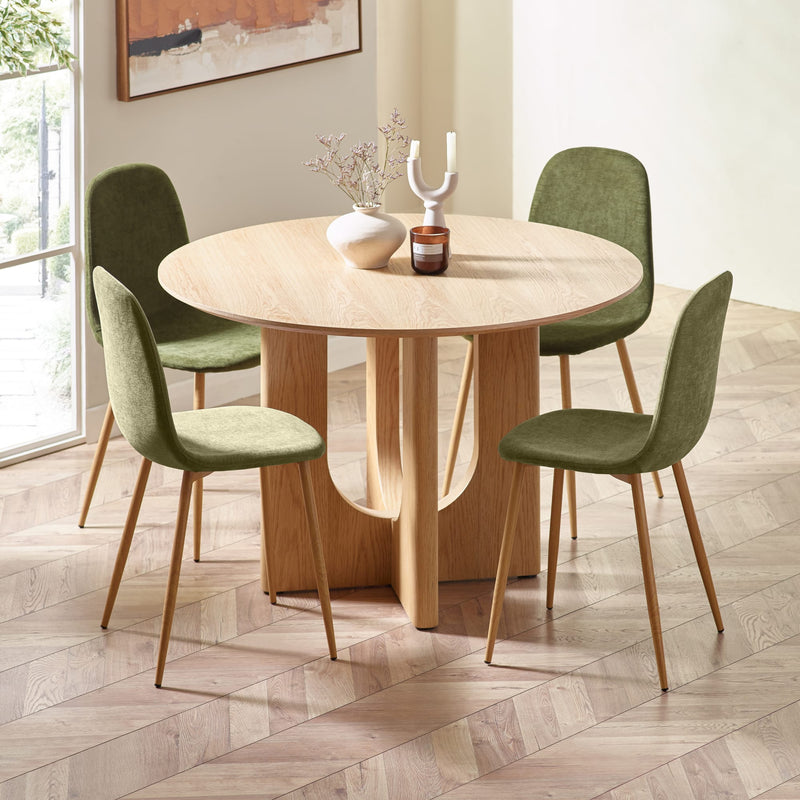 Dining table with four green chairs in a room with a large window.