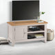 Light wood TV stand with a television on top in a room setting.