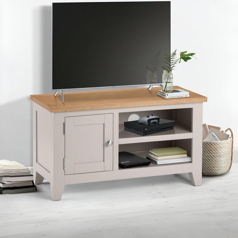 Light wood TV stand with a television on top in a room setting.