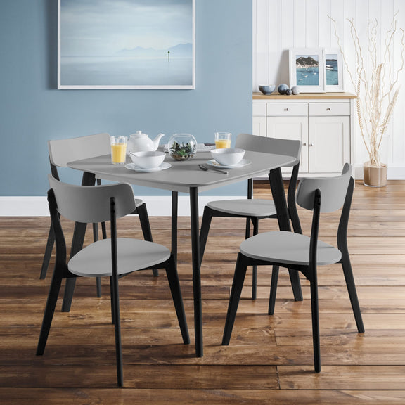 Dining table set with chairs in a room with a blue wall and wooden floor.