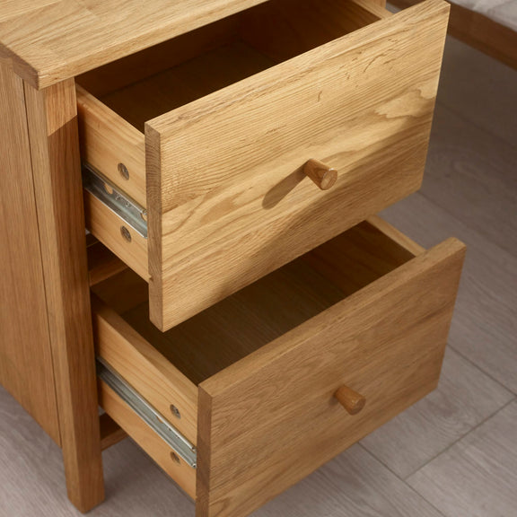 Wooden drawer unit with two open drawers on a wooden floor.
