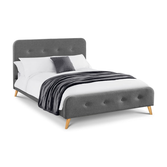 Gray upholstered bed with white bedding and a gray blanket on a white background