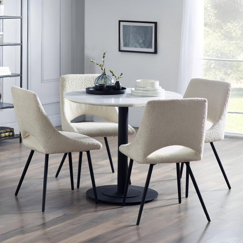 Dining room with a round table and four chairs in a well-lit room.